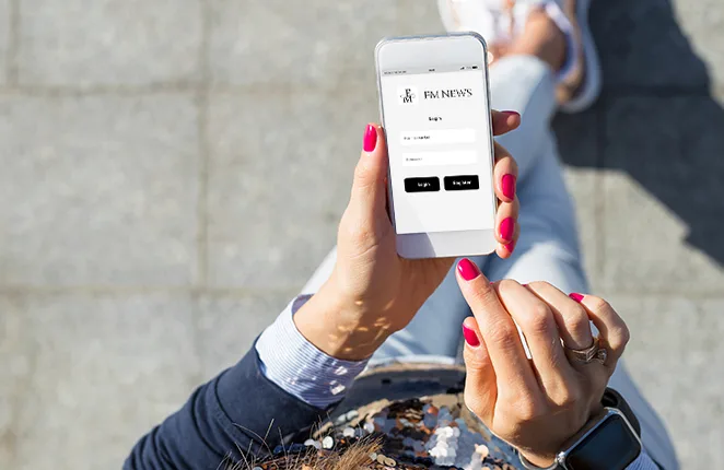 Kobieta trzyma smartfon z ekranem logowania aplikacji FM NEWS