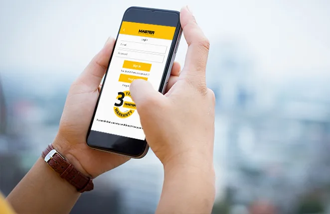 Dłonie trzymające smartfon z ekranem logowania aplikacji MASTER Climate Solutions