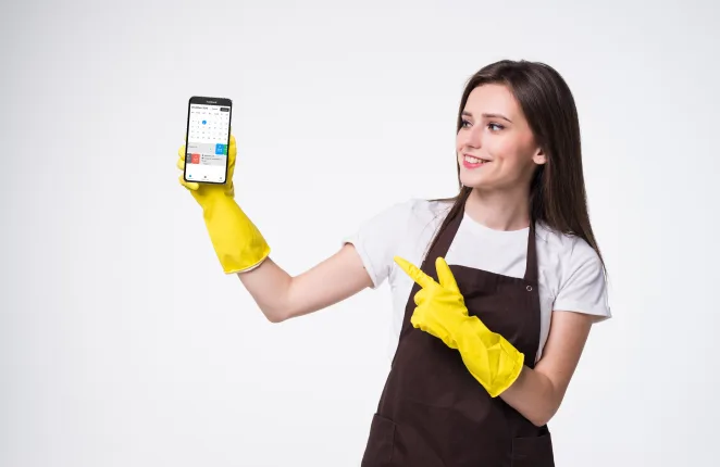Pracownica firmy sprzątającej w żółtych rękawicach wskazuje smartfon z aplikacją Concrete