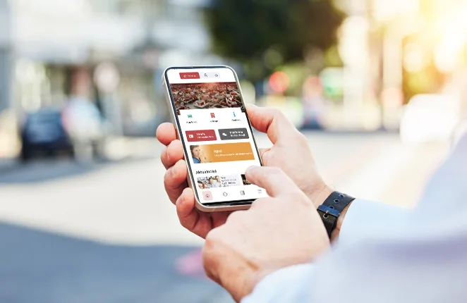 Smartfon z aplikacją Jarocin.pl w dłoniach na tle ulicy miasta